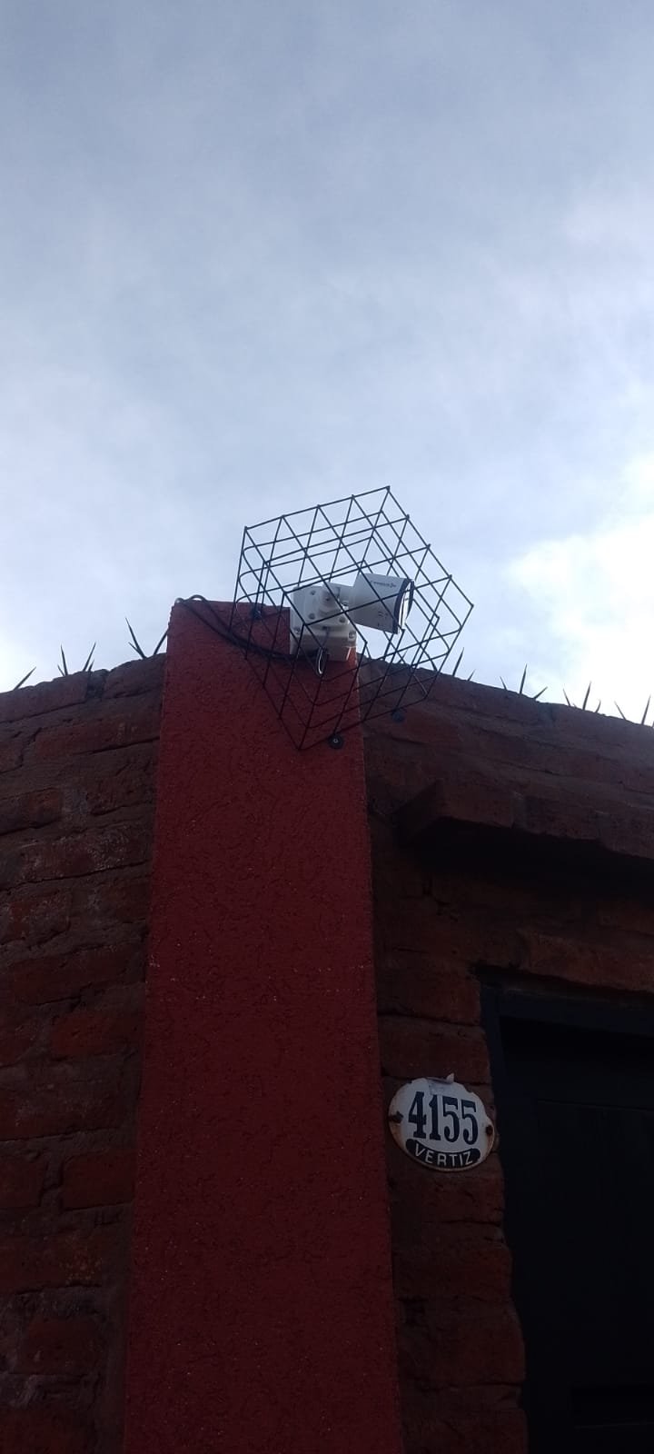 Instalación prolija de cámara en pilar de ladrillos a la vista en Vertiz 4155, protegida por una rejilla metálica negra antivandálica