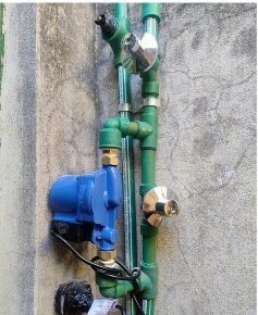 Bomba de agua y caños verdes sobre pared