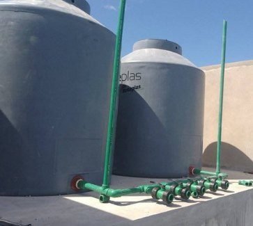 Instalación de tanques de agua con cañería verde sobre una losa
