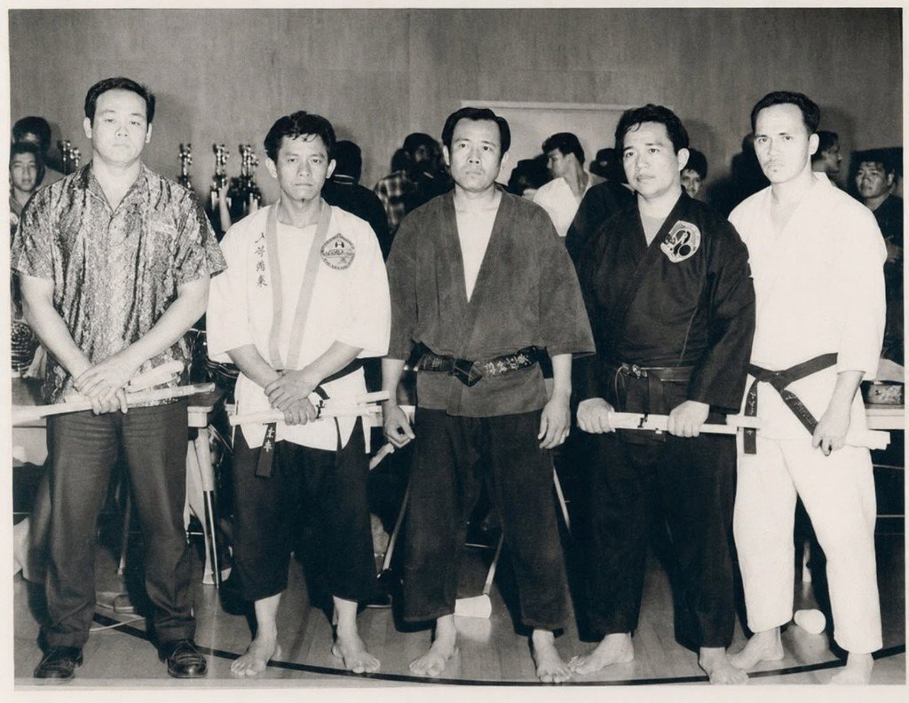 Fotografía histórica en blanco y negro de maestros con certificados en ceremonia marcial