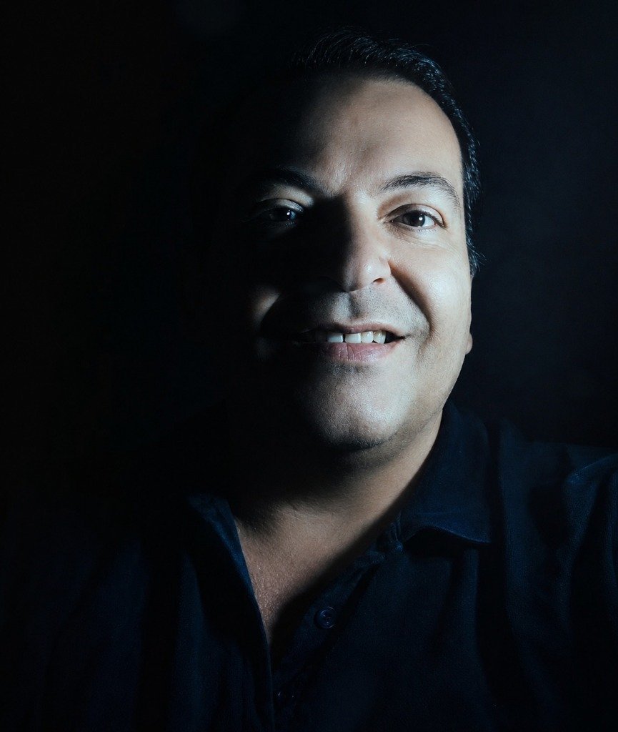 Retrato de Oscar Cáceres, sonriendo con fondo oscuro